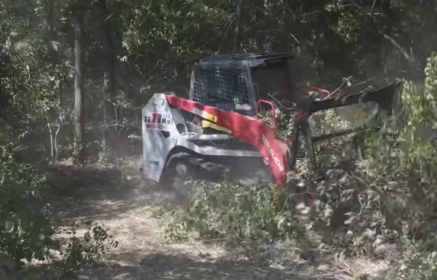 Takeuchi track loader with forestry mulching head clearing brush